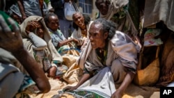 FILE - An Ethiopian woman argues with others over the allocation of yellow split peas distributed by the Relief Society of Tigray in the town of Agula, in the Tigray region of northern Ethiopia, on May 8, 2021.