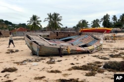 A boy walks past a fishing boat that was destroyed when Cyclone Kenneth struck in Pemba city on the northeastern coast of Mozambique, April, 27, 2019.