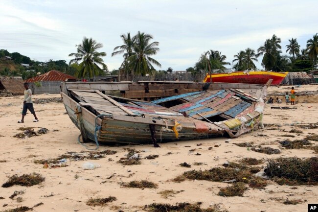 A boy walks past a fishing boat that was destroyed when Cyclone Kenneth struck in Pemba city on the northeastern coast of Mozambique, April, 27, 2019.