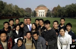 FILE - Former California Gov. Arnold Schwarzenegger poses for a group photo with students during a visit to Tsinghua University in Beijing Wednesday Nov. 16, 2005.