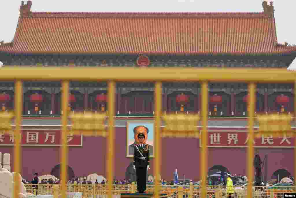 A paramilitary policeman stands guard before a giant portrait of late Chinese Chairman Mao Zedong at the Tiananmen gate, a day before the 19th National Congress of the Communist Party of China begins, in Beijing.