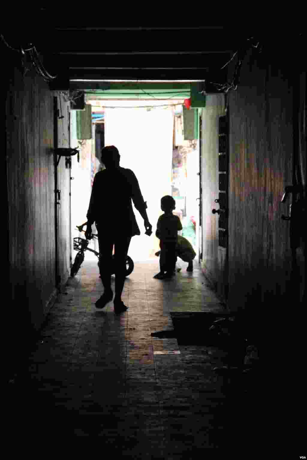 A resident and children walk through ​a dark corridor inside the White Building on Friday, September 5, 2014. (Nov Povleakhena/VOA Khmer) 