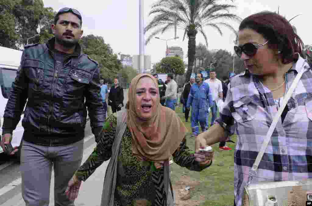 A woman is escorted out of the site of multiple bombings outside the main campus of Cairo University in Giza, near downtown Cairo, April 2, 2014.