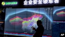 FILE - A worker is silhouetted against a computer display showing a live visualization of the online phishing and fraudulent phone calls across China during the 4th China Internet Security Conference (ISC) in Beijing, Aug. 16, 2016.
