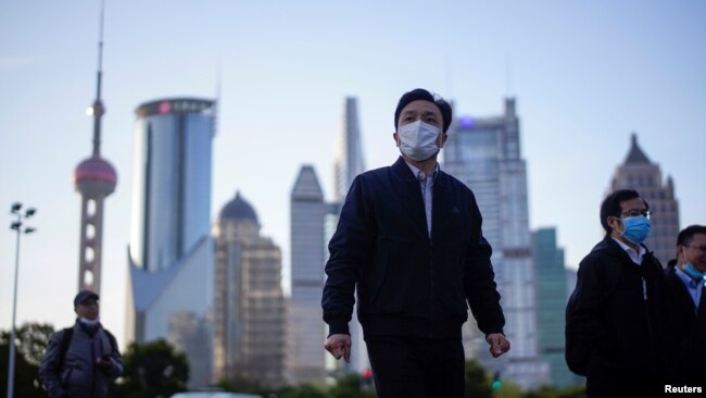 戴着口罩的行人行走在上海陆家嘴金融区的街道上。（2020年3月19日）