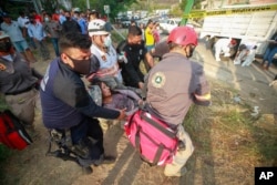 An injured migrant woman is moved by rescue personnel from the site of an accident near Tuxtla Gutierrez, Chiapas state, Mexico, Dec. 9, 2021.