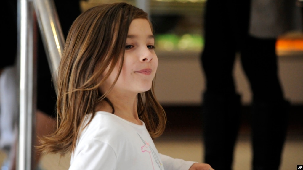 Liza Scott, who is running a lemonade stand to help fund her own brain surgery, holds a donation at her mother's bakery in Homewood, Alabama. (AP Photo/Jay Reeves)