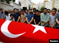 FILE - Friends and relatives of Habibullah Sefer, who was killed in Tuesday's attack at Istanbul airport, stand next to his flag-draped coffin during his funeral ceremony in Istanbul, June 30, 2016.