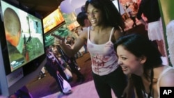 Members of the PMS Clan, a group of professional women gamers, Alexis Hebert, seated, and Felicia Williams play an X-Box game titled "Splinter Cell" at the Electronic Entertainment Exposition (E3) Friday, May 12, 2006, in Los Angeles. (AP Photo/Reed Saxon)