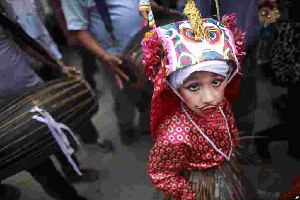 A Nepalese Hindu boy in festival attire walks in a procession during &quot;Gai Jatra,&quot; or Cow Festival in Kathmandu. Members of the Newar Community celebrate the festival in memory of their family members who died the preceding year, believing that the cow will guide them in their journey to heaven.