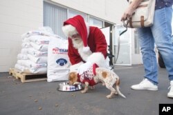 A PetSmart volunteer crew teams up with Santa Claus to load a truck with bags of free pet food for Rover's Retreat, a partner of San Diego Humane Society's PAWS program, on Tuesday, December 5, 2017 in San Diego.