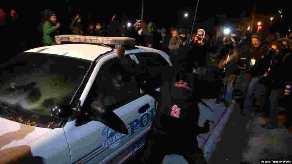 Protesters attack and turn over a police car outside Ferguson City Hall, in Ferguson, Missouri, Nov. 25, 2014.