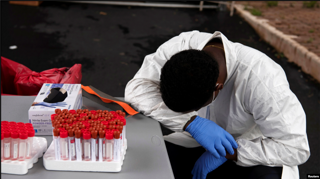 Një punonjës i shëndetësisë pushon ndërsa njerëzit vendosen në radhë me makina për t'u testuar për koronavirusin në Hjuston, Teksas