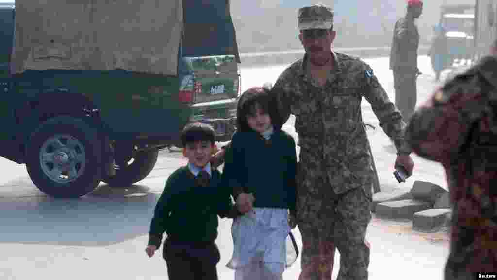 A soldier escorts schoolchildren from the school that was attacked by Taliban gunmen in Peshawar, Pakistan, Dec. 16, 2014.