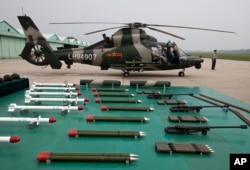 FILE - A military officer stands near a Z-9WZ attack helicopter and weapons, designed and manufactured by China, on the outskirts of Beijing, July 24, 2012. China has provided 35 percent of its arms to Pakistan from 2013 to 2017, according to the Stockholm International Peace Research Institute.