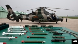 A military officer stands near a Z-9WZ attack helicopter and weapons, designed and manufactured by China, on display during a media oppotunity at a Chinese Liberation Army base, ahead of Army Day on the outskirts of Beijing.