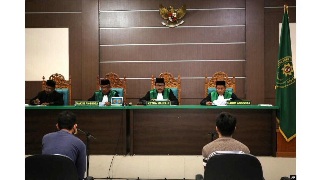 Two men accused of having gay sex sit on the defendants' chairs during their trial at Sharia court in Banda Aceh, Indonesia, May 10, 2017.