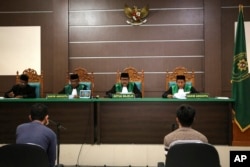 Two men accused of having gay sex sit on the defendants' chairs during their trial at Sharia court in Banda Aceh, Indonesia, May 10, 2017.