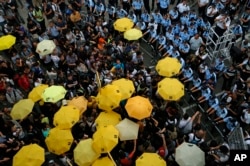 Protesters holding yellow umbrellas gather to observe a moment of silence to mark the first anniversary of "Umbrella Movement" outside the government headquarters in Hong Kong, Monday, Sept. 28, 2015.