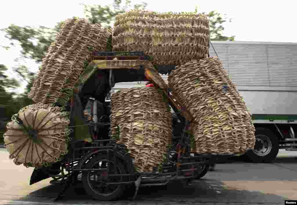 A man pedals his bicycle with a cart full of native abaca fans, which he will deliver to a market in Manila, Philippines.