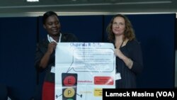 Mtisunge Mhango (left), program coordinator, and Nicola Desmond, a researcher at Malawi-Liverpool Welcome Trust, holding poster showing how Chipatala Robot program's colors work.