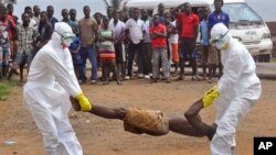 Des agents de santé plaçant le corps d'un homme, soupçonné de mourir du virus Ebola, dans un sac en plastique sous le regard d’une foule, à Monrovia, au Libéria, jeudi 4 septembre 2014 (AP Photo / Abbas Dulleh) 