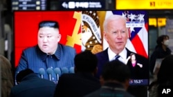 FILE - Commuters watch a TV showing file images of North Korean leader Kim Jong Un and U.S. President Joe Biden during a news program at the Suseo Railway Station in Seoul, South Korea, March 26, 2021.