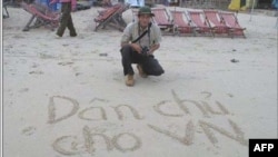 Blogger Ðiếu Cày và dòng chữ "Dân chủ cho Việt Nam" viết trên cát