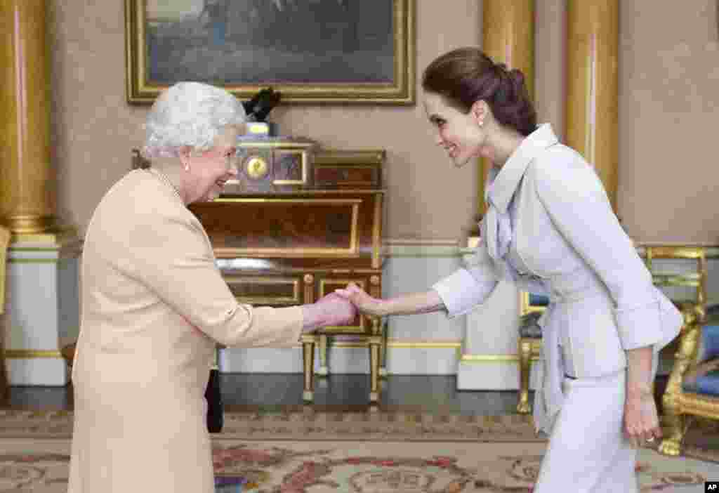 U.S actress Angelina Jolie, right, is presented with the Insignia of an Honorary Dame Grand Cross of the Most Distinguished Order of St. Michael and St. George by Britain's Queen Elizabeth II at Buckingham Palace, London.