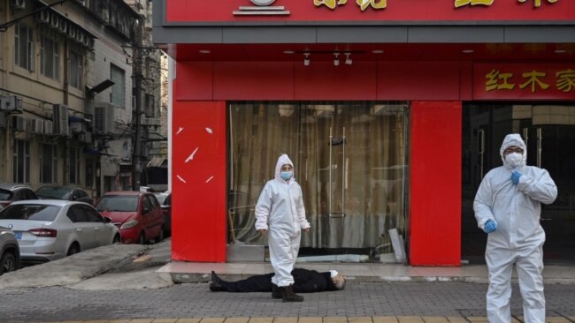 身穿防护服的中国卫生官员在检查一名在武汉一所医院附近倒地死亡的老年男子。(2020年1月30日)