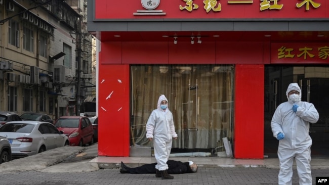身穿防护服的中国卫生官员在检查一名在武汉一所医院附近倒地死亡的老年男子的家。（2020年1月30日）