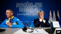 Atlet paralimpik Ukraina Grygorii Vovchinskyi menunjukkan tanda pengenalnya saat Presiden Komite Nasional Paralimpik Ukraina Valeriy Sushkevich menutup wajahnya dengan kedua belah tangannya dalam konferensi pers di Sochi (7/3).