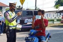 Petugas kepolisian membantu sosialisasi pemakaian masker kepada pengguna jalan di Kudus, Minggu, 13 Juni 2021. (Foto: Courtesy/Humas Pemkab Kudus)