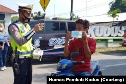 Petugas kepolisian membantu sosialisasi pemakaian masker kepada pengguna jalan di Kudus, Minggu, 13 Juni 2021. (Foto: Courtesy/Humas Pemkab Kudus)