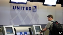 FILE - A man uses a United Airlines check-in kiosk at San Francisco International Airport in San Francisco. 