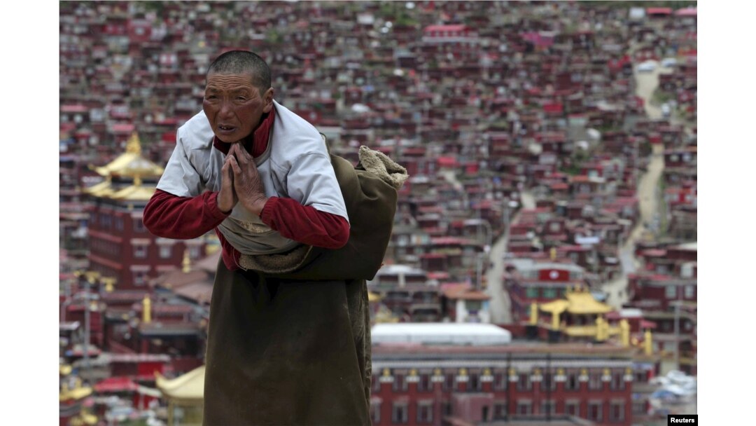 FILE - A Tibetan pilgrim prays near a Buddhist temple in Sertar County of Ganze Tibetan Autonomous Prefecture, Sichuan province, China, July 20, 2015.