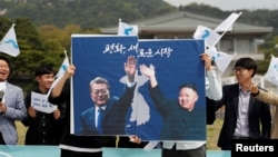Sinh viên cầm pa nô có hình tổng thống Nam Hàn và lãnh tụ Triều Tiên trên đường phố Seoul, ngày 26 tháng Tư, 2018, một ngày trước Thượng Đỉnh Liên Triều.
