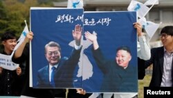 남북정상회담을 하루 앞둔 26일, 서울의 학생들이 문재인 한국 대통령과 김정은 북한 국무위원장의 사진이 들어있는 성공 기원 포스터를 들고 있다.