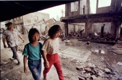 Warga etnis Tionghoa melewati rumah-rumah yang hancur dijarah dan dibakar massa dalam kerusuhan, 26 Mei 1998. (Foto: Reuters/Arsip)