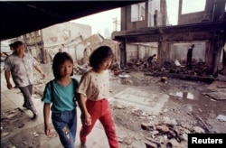 Warga etnis Tionghoa melewati rumah-rumah yang hancur dijarah dan dibakar massa dalam kerusuhan, 26 Mei 1998. (Foto: Reuters/Arsip)