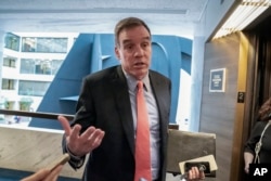 FILE - Senate Intelligence Committee Vice Chair Mark Warner, D-Va., speaks to reporters after a meeting on Capitol Hill in Washington, May 9, 2019.