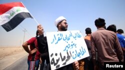 A protester holds a sign that reads "We ask the decision makers to provide the things we are deprived of" during a protest in south of Basra, Iraq, July 16, 2018. 