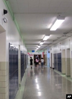 In this July 10, 2018 photo, students walk down a hallway at Lockport High School in Lockport, N.Y. On the upper left a camera with facial recognition capabilities hangs on the wall waiting for its installation to be completed. (AP Photo/Carolyn Thompson)