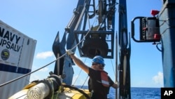 FILE - Tucker Bailey guides a towline through the A-frame while deploying the tow pinger aboard USNS Apache, Oct. 24, 2015. 