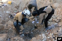 In this photo provided by the Syrian Civil Defense group known as the White Helmets, shows members of Civil Defense removing a dead body from under the rubble after airstrikes hit in Aleppo, Sept. 24, 2016.