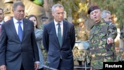 Le chef de l'Otan Jens Stoltenberg, au centre, accompagné du président roumain Klaus Iohannis et du colonel roumain Daniel Cristian Dan, à droite, lors d’une visite à la brigade multinationale à Craiova, Roumanie, 9 octobre 2017.