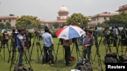 Television journalists are seen outside the Supreme Court building in New Delhi, India, Aug. 22, 2017.