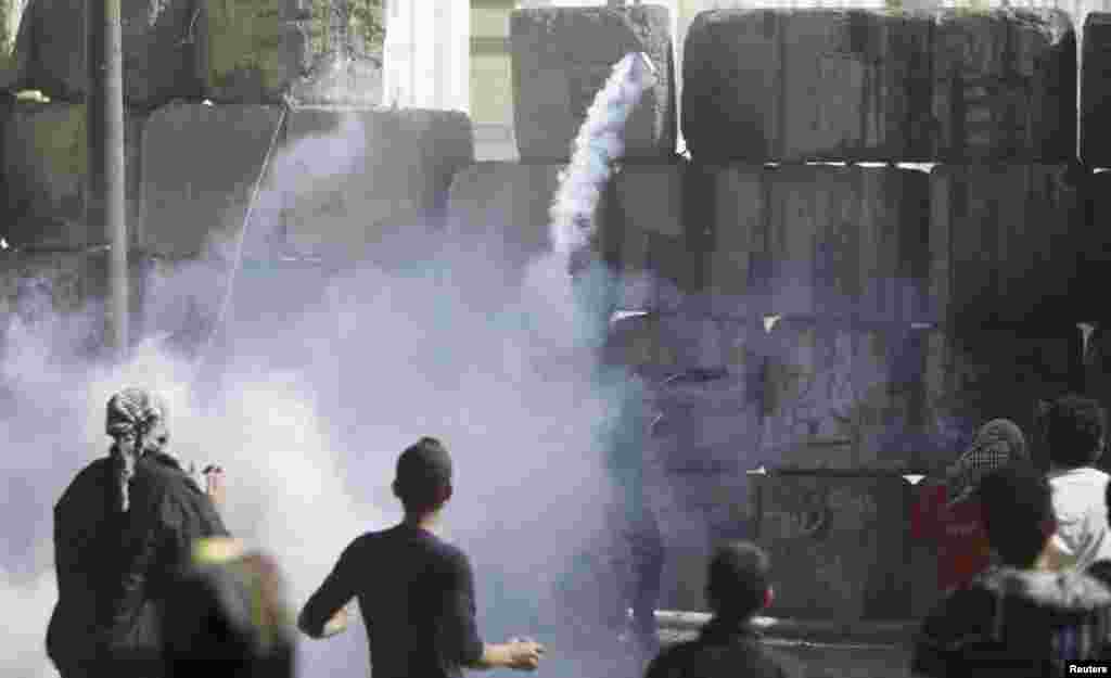 A protester opposing Egyptian President Mohamed Morsi throws a tear gas canister, earlier thrown by riot police near Tahrir Square, Cairo, Egypt, January 25, 2013.