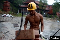 FILE - Shi Shenwei pulls a wheelbarrow at the construction site of a Buddhist temple in the village of Huangshan, in Fujian Province, China, on September 28, 2016.