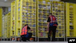 This picture shows workers inspecting transport's robots, which bring the ordered products directly to the employees, at the distribution center of US online retail giant Amazon in Moenchengladbach, on December 17, 2019. (Photo by INA FASSBENDER / AFP)